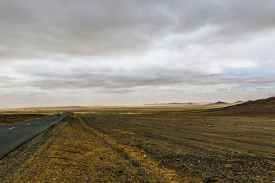 Road amidst field against sky