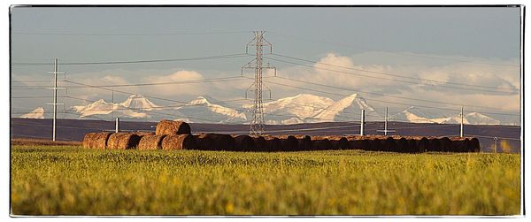 Electricity pylon on field against sky