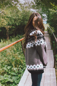 Rear view of woman standing against trees