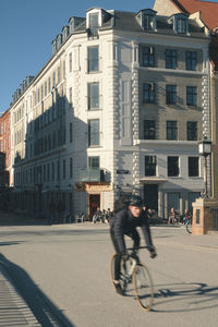 Man riding bicycle on city street against buildings