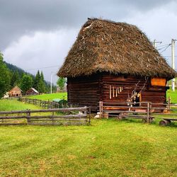 Old house on field against cloudy sky