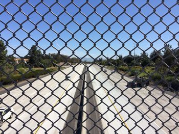 Cars on road seen through chainlink fence