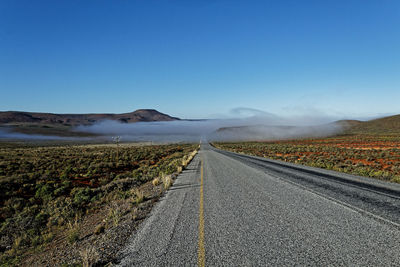 Surface level of road against clear blue sky