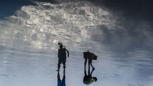 Reflection of people on sea shore