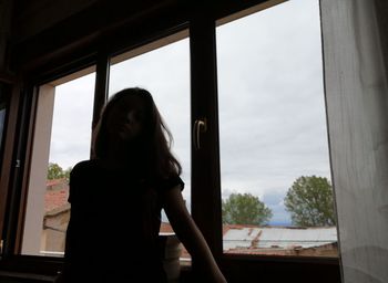 Woman looking through window at home