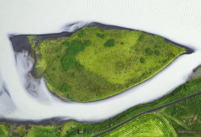 Drone view of rough rocky brown formations surrounded by lush green plants covered with thick fog in nature of iceland