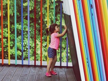 Girl drawing on blackboard by colorful railing on porch