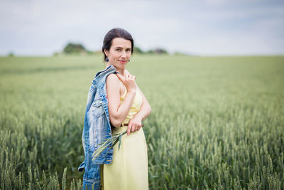 Lifestyle portrait of young stylish woman walking by wheat field