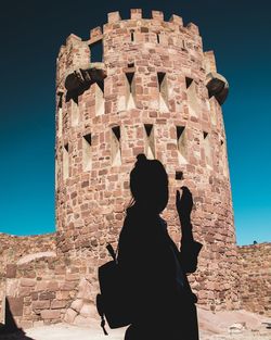 Rear view of woman standing against old building