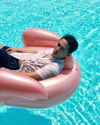 Portrait of man relaxing on inflatable raft in pool