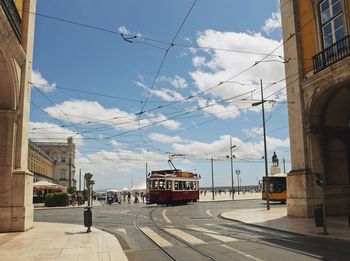 Tramway on city street amidst buildings against sky