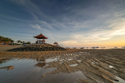 Lifeguard hut on beach by sea against sky during sunset