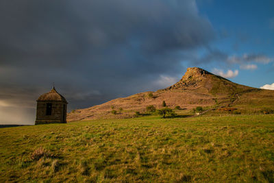 Church on field by mountain against sky