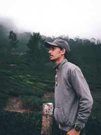 Side view of young man standing against mountain