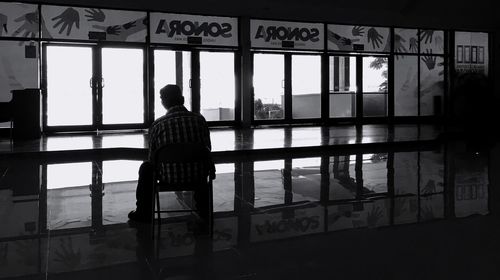 Rear view of man standing by window