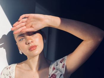 Close-up young woman with shielding eyes against wall