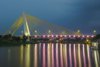 Illuminated suspension bridge over river at night