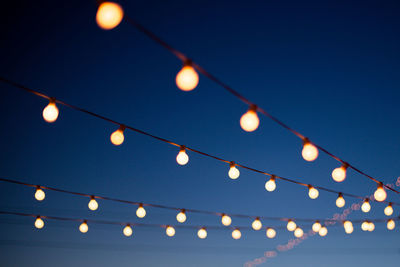 Low angle view of illuminated light bulb against sky at night