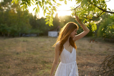 Woman standing by tree trunk