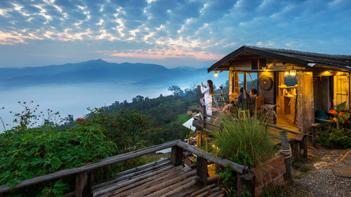 Rear view of woman photographing mountain against sky during sunrise 