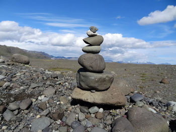 Stack of stones on rock against sky