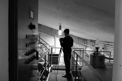 Silhouette man standing on elevated walkway in illuminated building