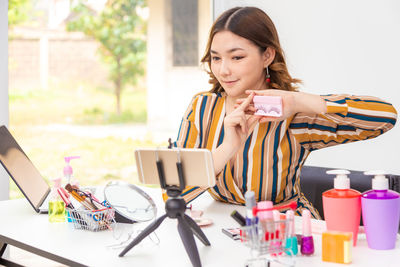 Woman using phone while sitting on table