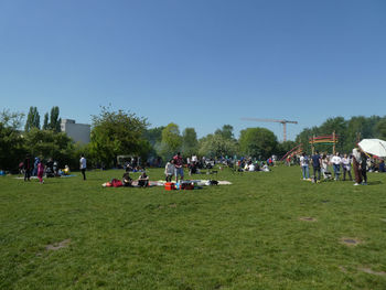 People playing on field against clear sky