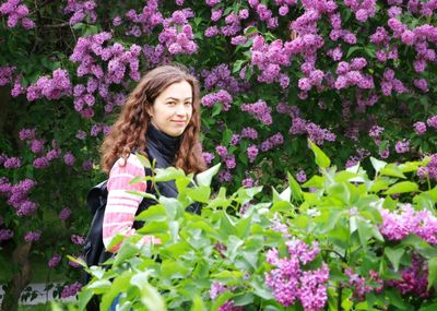 Portrait of smiling woman standing by pink flowers