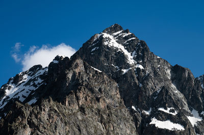 Low angle view of snowcapped mountains against clear blue sky