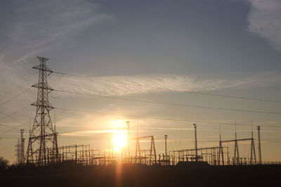 Electricity pylon against dramatic sky during sunset