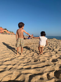 Rear view of mother and daughter on beach