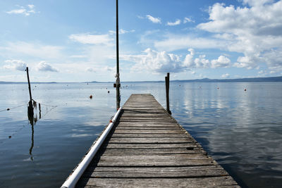 Wooden jetty on pier over sea against sky