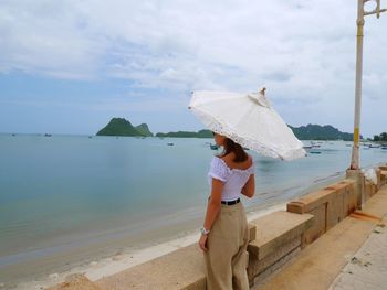 Woman standing on beach against sky