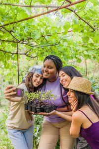 Portrait of smiling friends standing against trees