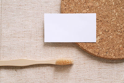 Directly above shot of blank visiting card by toothbrush on table