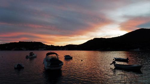 Boats in lake against sky during sunset