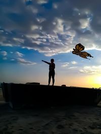 Close-up of butterfly flying with woman in background against sky