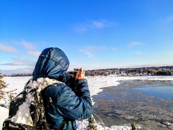 Rear view of person photographing sea against sky