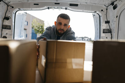 Young delivery person arranging boxes in van