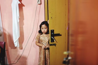 Portrait of girl standing by door at home