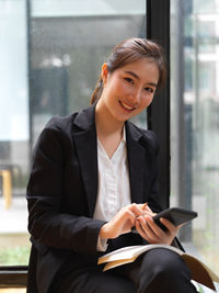 Portrait of young businesswoman using smart phone sitting outdoors