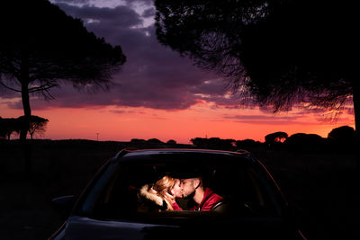 Young couple kissing in car during sunset