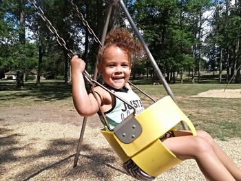 Portrait of girl swinging in swing at park