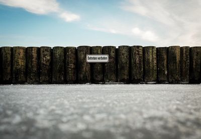 Text on groyne against sky