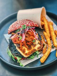 Close-up of halloumi and mushroom burger with french fries served in plate.