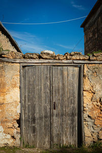Abandoned building and old wooden door against blue sky