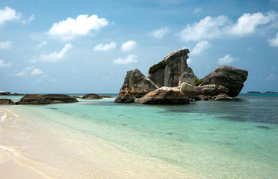 Rock formation by sea against sky