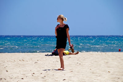 Full length of woman standing on beach against sky