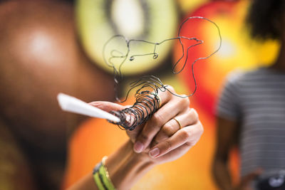 Cropped hand of person holding wire decoration